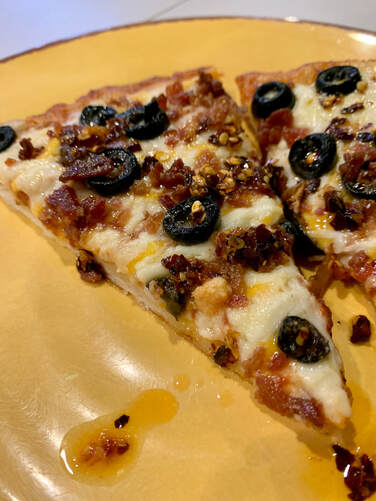 Store bought cheese pizza topped with bacon, olives, parmesan, and chili garlic oil.